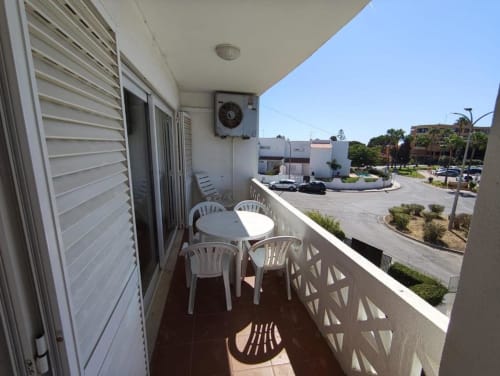 Terraço ensolarado com mesa e cadeiras brancas com vista para a rua de Albufeira, apartamento Albufeira Inn perto da Praia dos