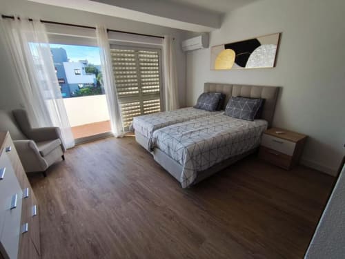 Quarto moderno na Albufeira Inn com cama de casal, varanda com vista para o terraço, pisos em madeira e móveis contemporâneos