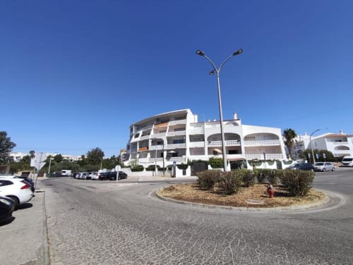 Edifício Albufeira Inn em Praia dos Aveiros, Portugal, com varandas brancas curvas e estacionamento na rua