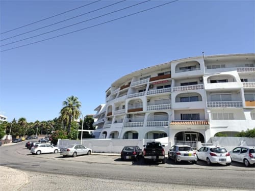 Edifício moderno do Albufeira Inn com varandas curvas, carros estacionados e palmeiras em Praia dos Aveiros