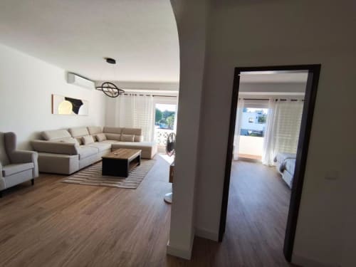 Sala de estar moderna com sofá bege, zona de refeições e entrada para quarto no apartamento à beira-mar Albufeira Inn