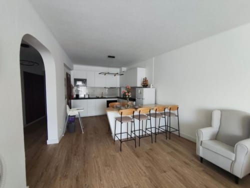 Apartamento T1 moderno em Albufeira com cozinha aberta, zona de refeições, pavimento em madeira e espaço acolhedor perto da praia.