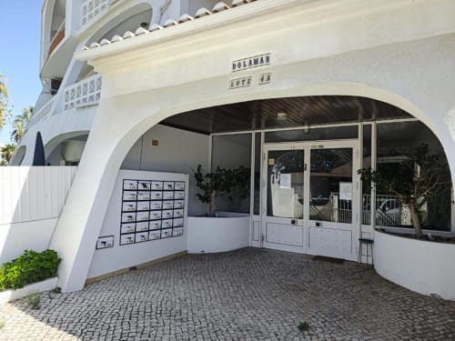 Entrada do edifício de apartamentos Albufeira Inn, Dolamar Lote S.A., com arquitetura moderna branca e curvilínea