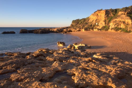 Falésias douradas e praia de areia ao pôr do sol em Albufeira, Portugal perto do Albufeira Inn