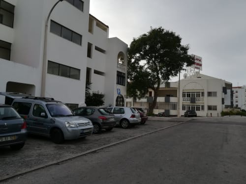Estacionamento do Albufeira Inn com edifício de apartamentos branco e carros estacionados em Albufeira, Portugal