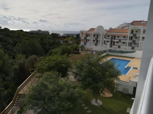 Varanda do apartamento Albufeira Inn com vista para a piscina, jardins exuberantes e oceano em Portugal