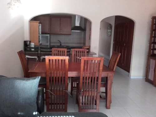 Sala de jantar com mesa e cadeiras de madeira no apartamento em Albufeira, cozinha visível ao fundo