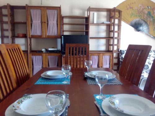 Zona de refeições do apartamento em Albufeira com mesa de madeira, louça de mesa e prateleiras com ventilador decorativo