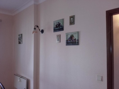 Quarto com paredes rosa na Albufeira Inn, com quadros emoldurados, arandela de parede e porta de entrada.