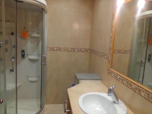 Casa de banho moderna com lavatório branco, espelho e cabine de duche no apartamento Albufeira Inn, Portugal