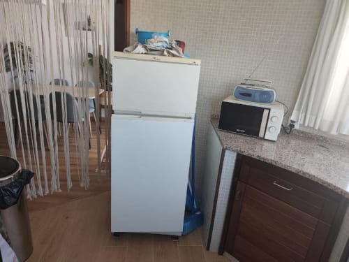 Área de cozinha do apartamento Albufeira Inn com refrigerador, micro-ondas e fogão brancos