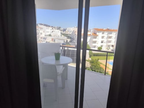 Varanda de apartamento em Albufeira com mesa branca, vista para o oceano e edifícios residenciais sob céu limpo