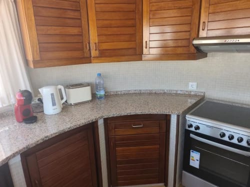 Cozinha do apartamento Albufeira Inn com armários de madeira, bancada em granito, fogão elétrico e eletrodomésticos
