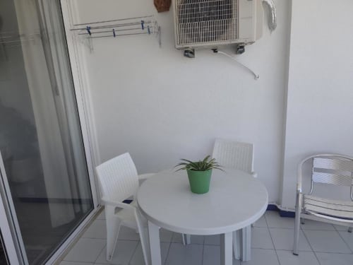 Terraço luminoso do Albufeira Inn com mesa redonda branca, cadeiras, planta em vaso e unidade de ar condicionado na parede