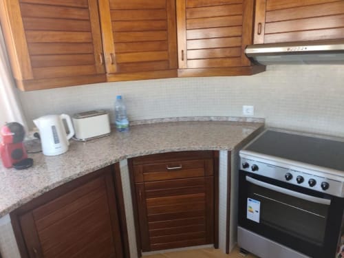 Cozinha do apartamento Albufeira Inn com armários em madeira, bancada em granito e fogão em aço inoxidável