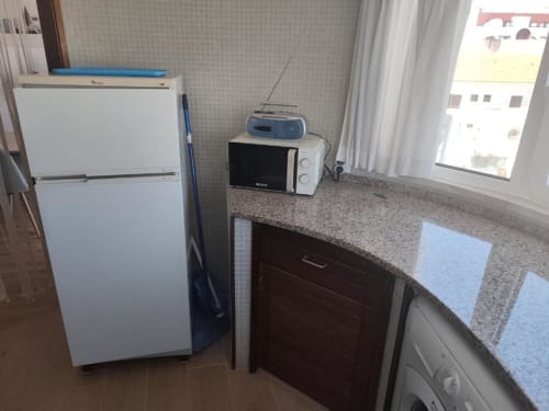 Cozinha do apartamento Albufeira Inn com frigorífico branco, micro-ondas e eletrodomésticos com vista para a cidade