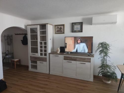 Sala de estar moderna do Albufeira Inn com móveis brancos, TV de ecrã plano e planta em vaso em Albufeira, Portugal