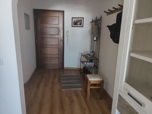 Entrada do apartamento Albufeira Inn com porta de madeira, cabideiro, banco e prateleiras abertas em Albufeira, Portugal