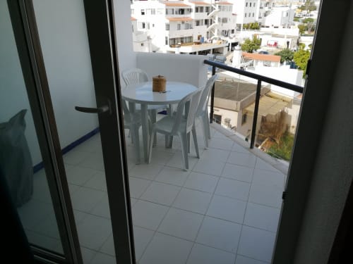 Varanda com mesa de jantar no apartamento Albufeira Inn, com vista para edifícios brancos e pátio no Algarve
