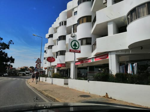 Edifício moderno de apartamentos com curvas brancas e supermercado Spar no piso térreo em Albufeira, Portugal