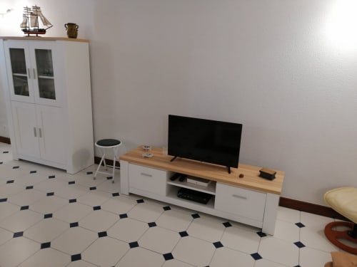 Sala de estar moderna no Albufeira Inn com TV de tela plana, unidade de armazenamento branca, suporte de madeira para TV e modelo decorativo de veleiro