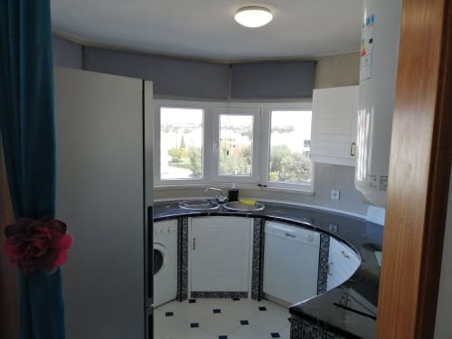 Cozinha moderna em apartamento em Albufeira com máquina de lavar louça, máquina de lavar roupa e janela com vista para a piscina