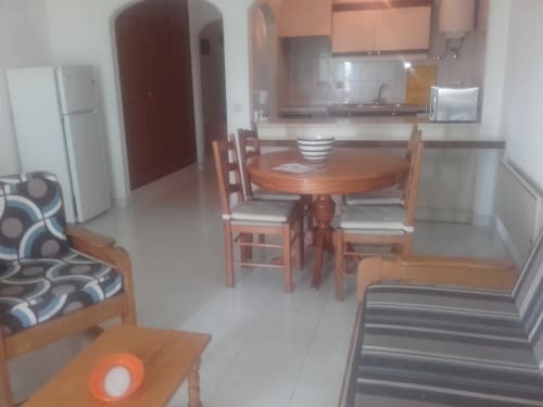 Cozinha integrada e zona de refeições no apartamento de Albufeira com mesa de madeira, cadeiras, kitchenette e móveis modernos