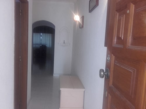 Corredor do apartamento Albufeira Inn com portas de madeira, paredes brancas e janela em arco com cortinas