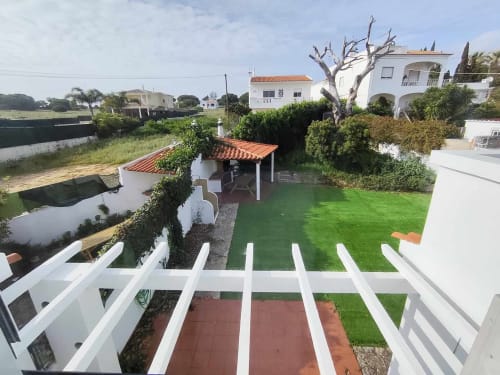Villa Olhos de Água com jardim bem cuidado, terraço com pérgula de telha vermelha, varandas brancas e vista para o waterfront em Albufeira