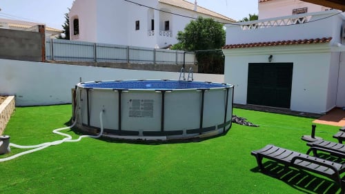 Piscina elevada em jardim impecável da villa Albufeira Inn em Olhos de Água, Portugal, com espreguiçadeiras e branco