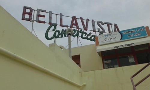 Placa de néon vintage da Cafeteria Bela Vista em Albufeira, Portugal, acima da entrada amarela com lojas locais