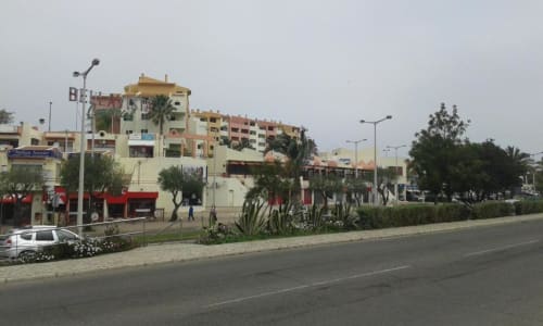 Vista exterior da Albufeira Inn com edifício residencial de vários andares, palmeiras e iluminação urbana em Portugal