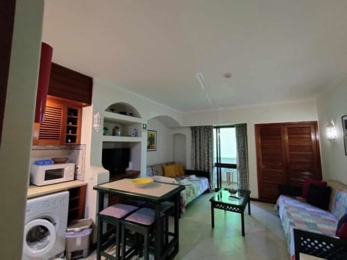 Estúdio em Albufeira com kitchenette, mesa de jantar, camas, TV e varanda com vista para jardim e piscina