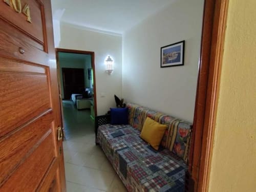 Quarto de estúdio na Albufeira Inn com cama de solteiro, padrão listrado, almofada amarela, portas de madeira, paredes brancas e azulejos