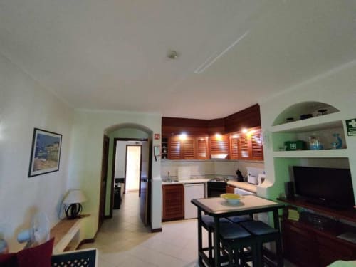 Cozinha e sala de jantar modernas no Albufeira Inn com armários de madeira, mesa de refeições e prateleiras com detalhes em verde