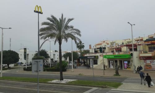 McDonald's e lojas no centro de Albufeira com palmeiras e vista da rua da zona de resort PT