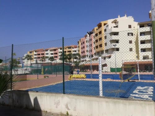 Quadra de ténis do Albufeira Inn com edifícios residenciais coloridos de fundo em Albufeira, Portugal