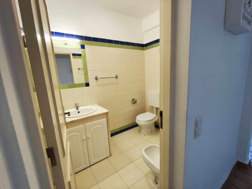 Casa de banho moderna em vivenda em Albufeira com azulejos creme, detalhes azuis, lavatório, sanita e base de duche em Olhos de