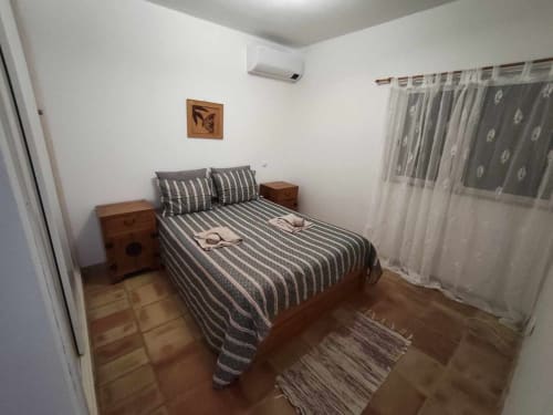 Quarto espaçoso com roupa de cama às riscas, mesas de cabeceira em madeira e cortinas translúcidas na villa Albufeira Inn em Olhos de Água,