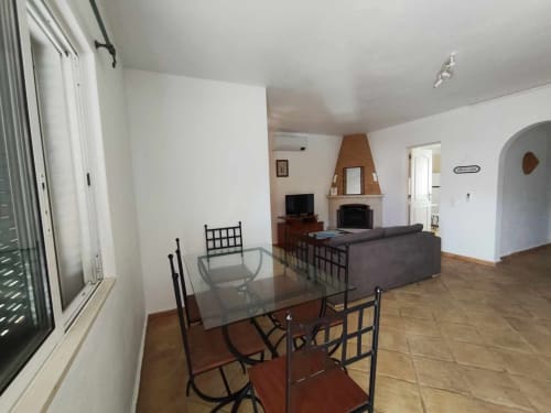 Sala de estar em conceito aberto na villa Albufeira Inn com mesa de jantar, sofá, lareira e acesso ao terraço
