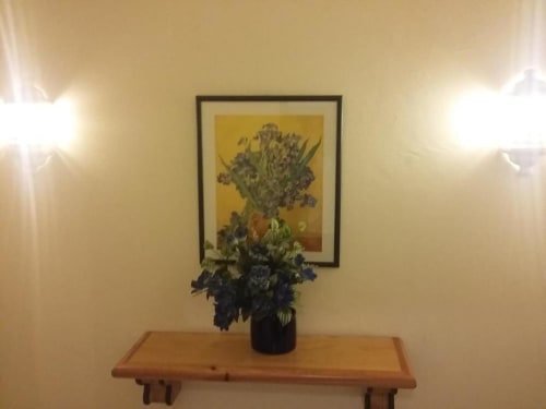 Mesa de madeira com vaso preto de íris abaixo de pintura de íris emoldurada no apartamento de Albufeira
