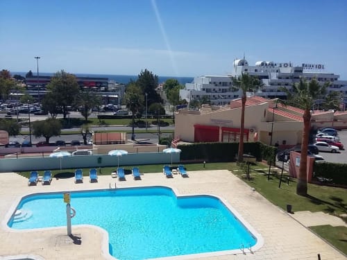 Piscina do Albufeira Inn com espreguiçadeiras azuis, vista para o mar e edifícios brancos do Mediterrâneo em Albufeira, Portugal