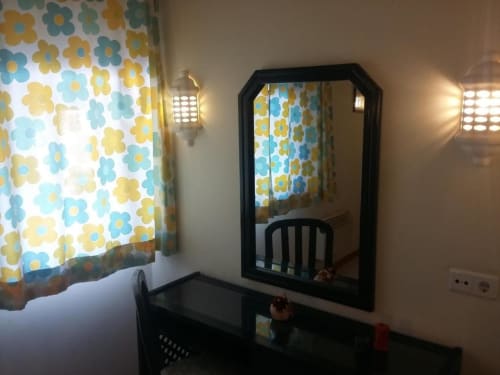 Quarto moderno com espelho de moldura preta, cortinas florais e móveis contemporâneos no apartamento Albufeira Inn