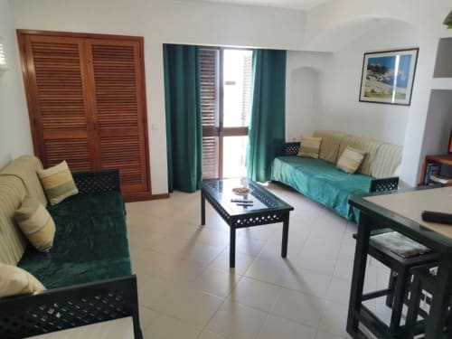 Sala de estar luminosa em apartamento em Albufeira com área de estar, acesso ao terraço e vista para o jardim