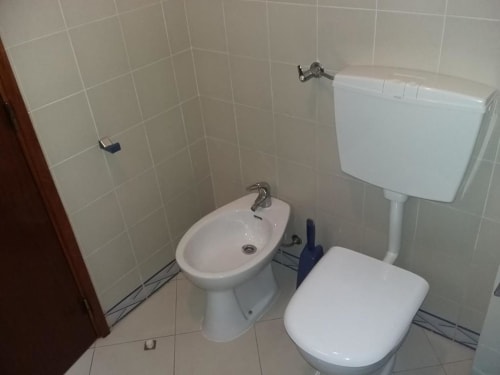 Casa de banho do apartamento Albufeira Inn com sanita, bidé e caixa de descarga brancos em Portugal