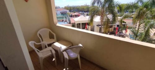 Varanda iluminada da Albufeira Inn com cadeiras de plástico branco com vista para o jardim e piscina deste apartamento de aluguel no Algarve
