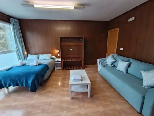Amplia habitación de hotel en Las Mellis, Antequera, con cama, sofá, paredes de madera y comodidades modernas