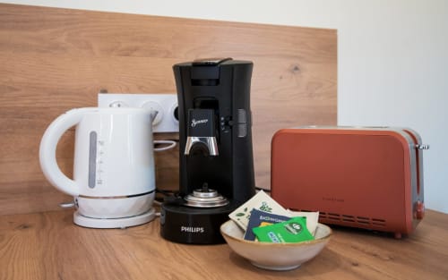 Electrodomésticos de la villa: hervidor eléctrico blanco, cafetera Philips negra, tostadora color óxido y surtido de infusiones