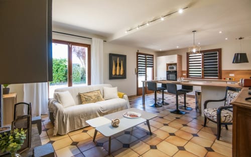 Amplio salón de villa con sofá crema, cocina moderna, comedor y suelo de baldosas de terracota en Millau, Francia