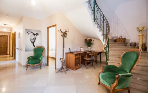 Elegante habitación abuhardillada en villa de Millau con sillas de terciopelo verde, escritorio de madera, escalera curva y decoración clásica
